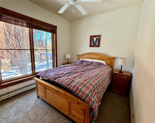 carpeted bedroom with multiple windows, ceiling fan, and a baseboard heating unit