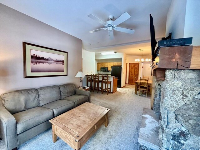 carpeted living room with ceiling fan with notable chandelier