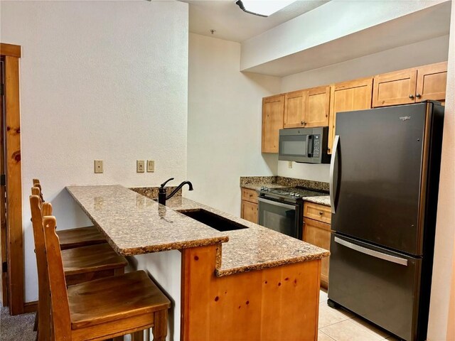 kitchen featuring sink, a kitchen breakfast bar, black electric range, kitchen peninsula, and fridge