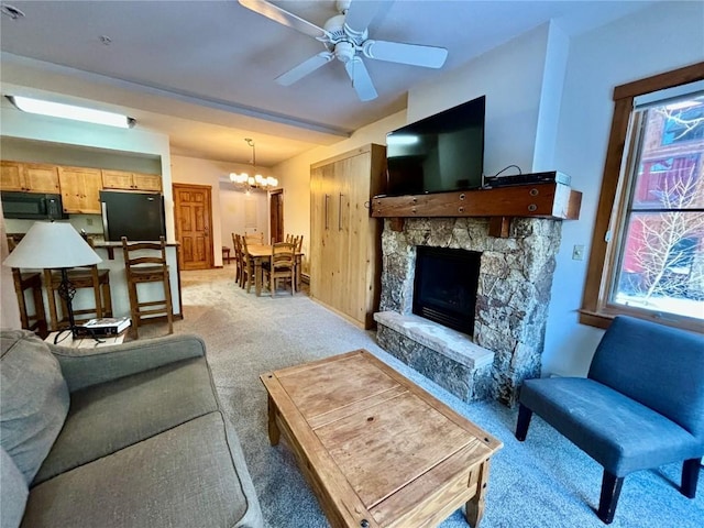 carpeted living room featuring a fireplace, beam ceiling, and ceiling fan with notable chandelier