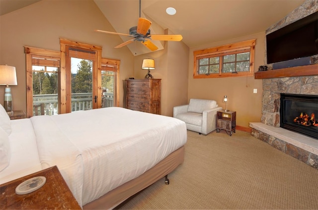 bedroom with access to exterior, light colored carpet, a ceiling fan, vaulted ceiling, and a stone fireplace