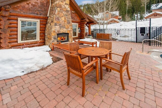 snow covered pool with an in ground hot tub and a patio area