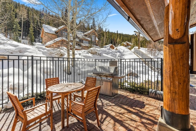 snow covered deck featuring a patio, a grill, fence, exterior kitchen, and outdoor dining space