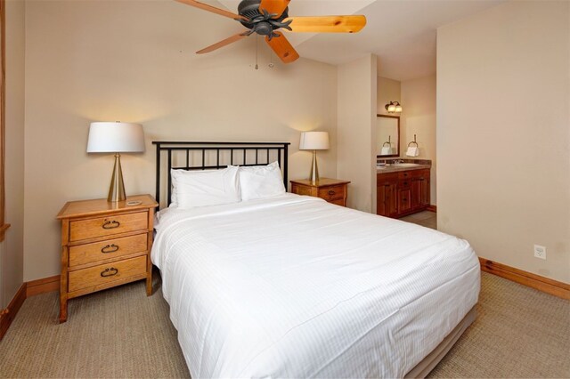 bedroom with baseboards, connected bathroom, and light colored carpet