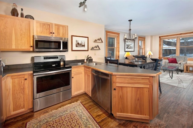 kitchen featuring pendant lighting, sink, stainless steel appliances, and kitchen peninsula