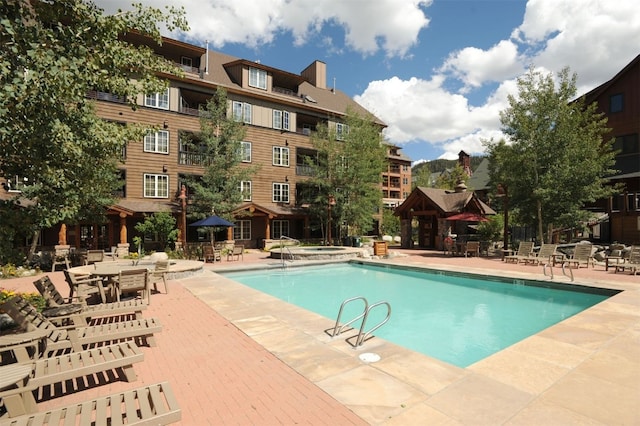 view of pool featuring a community hot tub and a patio area