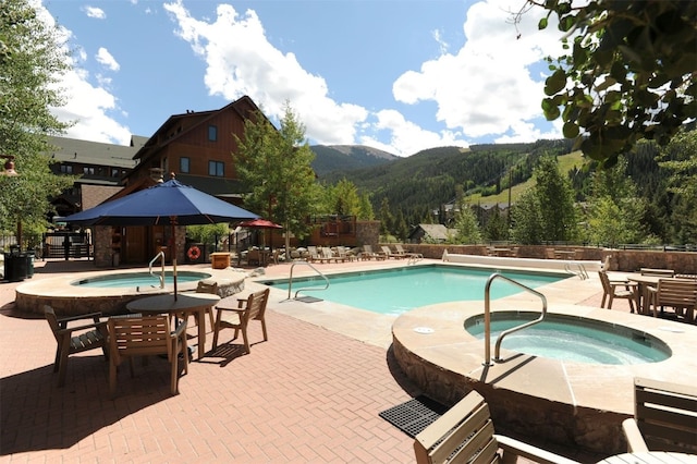 view of pool featuring a mountain view, a patio area, and a hot tub