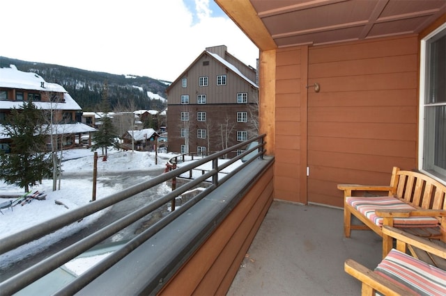 snow covered back of property featuring a mountain view