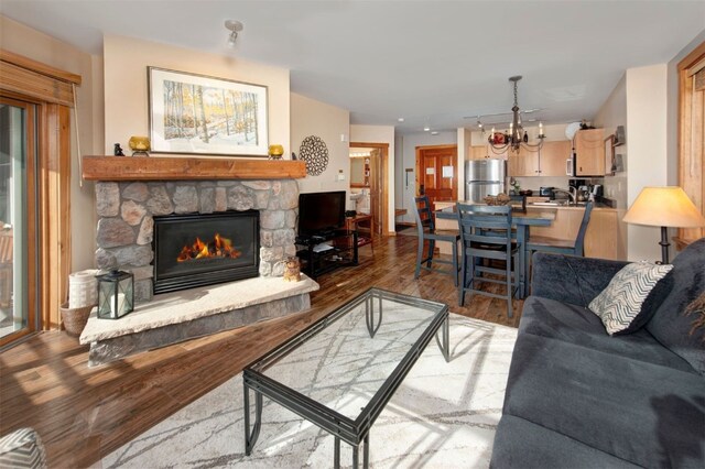 living room with wood-type flooring, a fireplace, and a chandelier