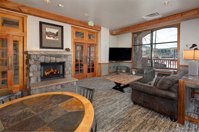 living room with a stone fireplace and french doors