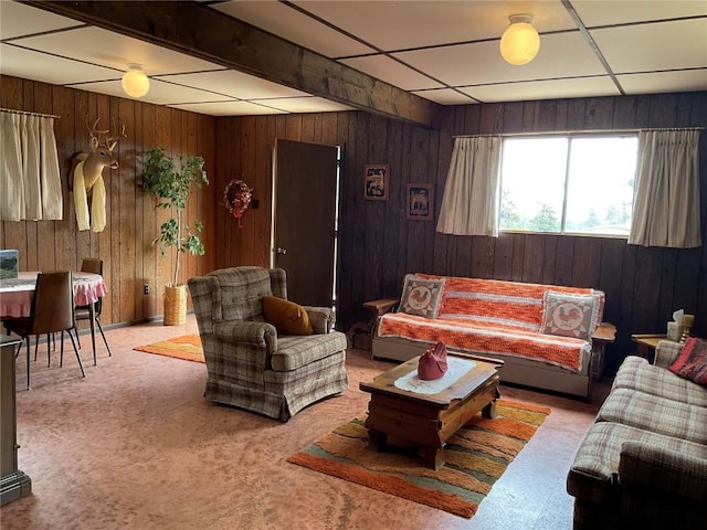 carpeted living room with wooden walls and a drop ceiling