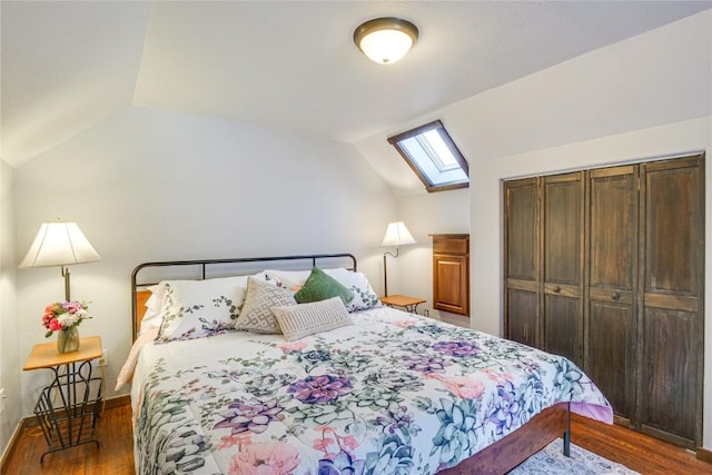 bedroom featuring vaulted ceiling with skylight, wood finished floors, a closet, and baseboards