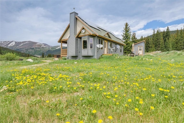 view of side of property featuring solar panels, a mountain view, and a chimney