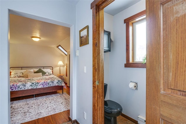 bedroom featuring wood finished floors, baseboards, and a baseboard radiator