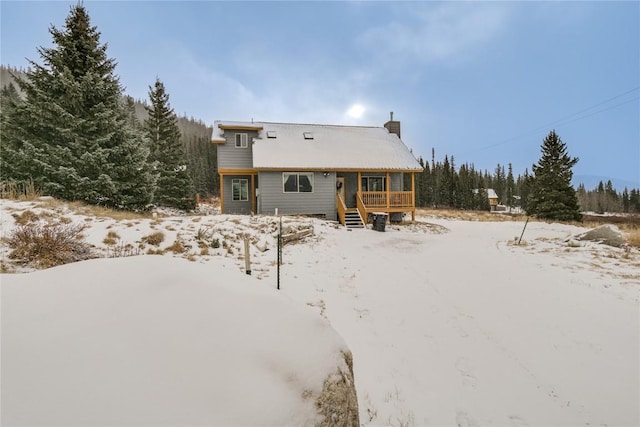 snow covered back of property featuring a chimney and a deck