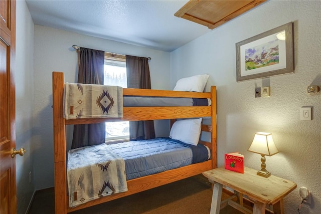 bedroom featuring attic access and a textured wall