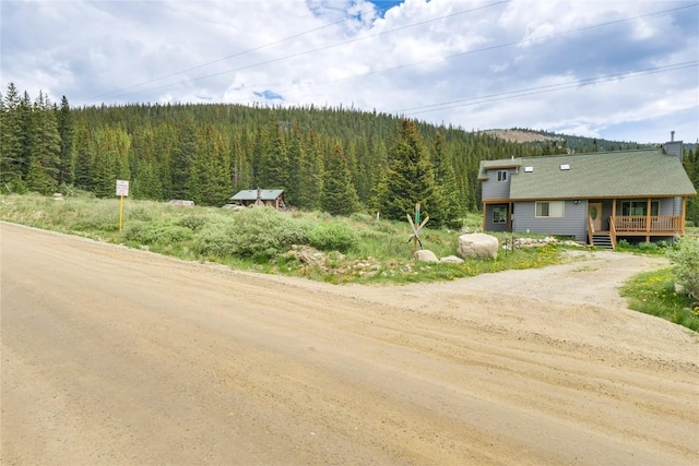 view of road featuring a wooded view and dirt driveway