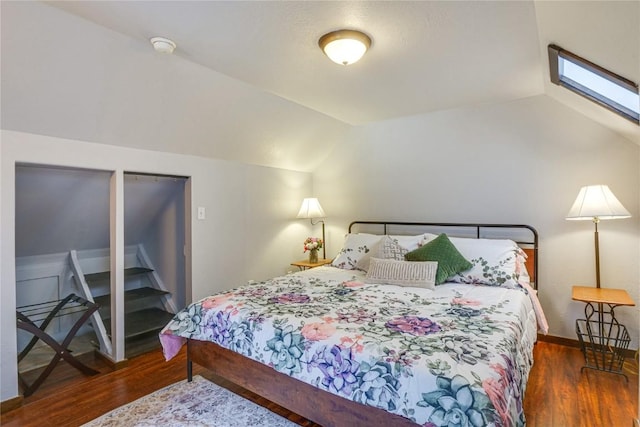 bedroom with lofted ceiling with skylight, baseboards, and wood finished floors