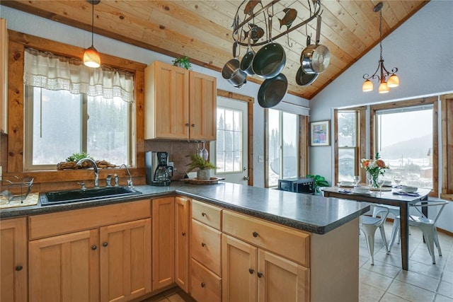 kitchen featuring dark countertops, plenty of natural light, a peninsula, and a sink