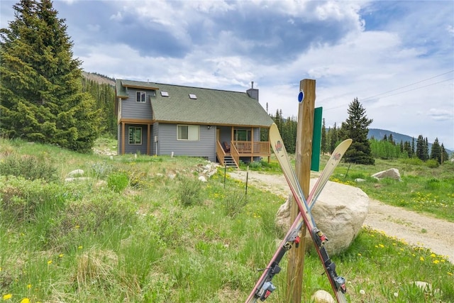 rear view of house featuring a deck with mountain view and a chimney