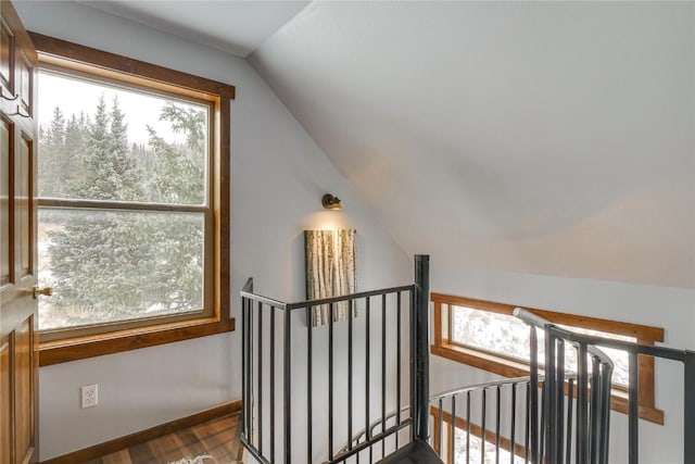 stairway with baseboards, lofted ceiling, plenty of natural light, and wood finished floors