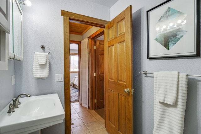 bathroom featuring a sink, connected bathroom, a textured wall, and tile patterned flooring