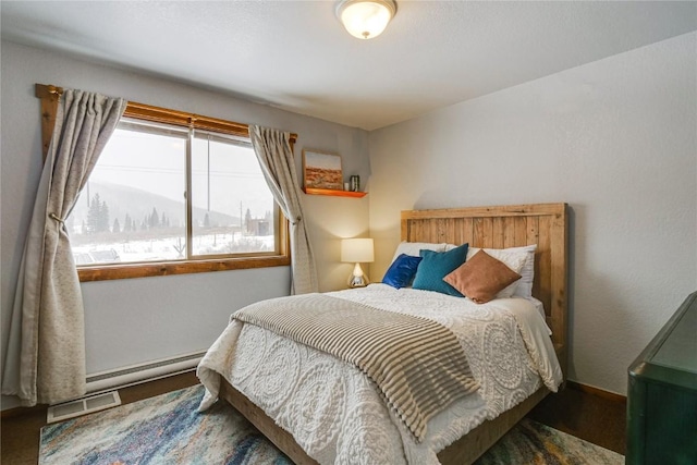 bedroom featuring a baseboard heating unit, baseboards, and visible vents