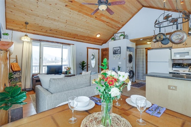 living area with wood ceiling, high vaulted ceiling, stacked washing maching and dryer, and ceiling fan