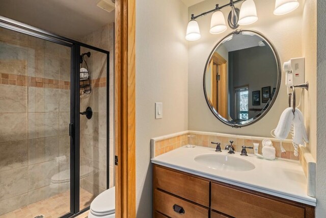 bathroom featuring vanity, an enclosed shower, and toilet