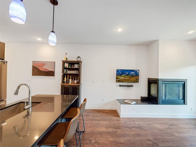 interior space with pendant lighting, sink, a kitchen breakfast bar, and hardwood / wood-style floors