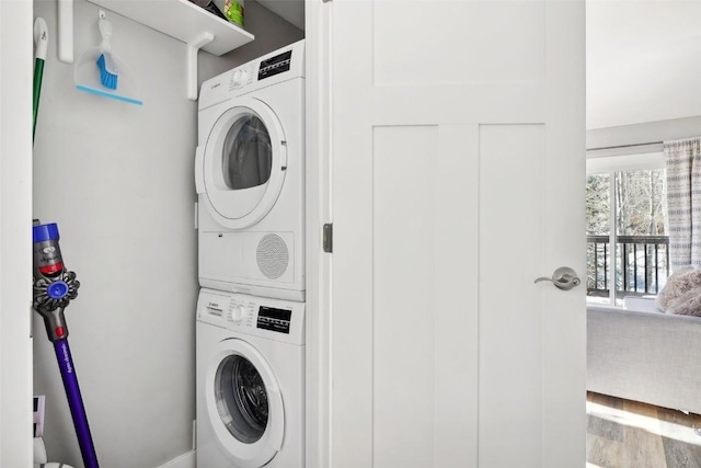 clothes washing area featuring stacked washer and dryer, wood finished floors, and laundry area