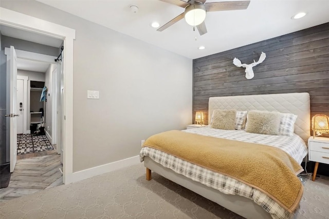 bedroom with baseboards, ceiling fan, an accent wall, wood walls, and recessed lighting