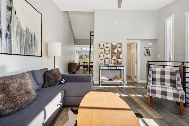 living area featuring high vaulted ceiling, dark wood finished floors, and baseboards