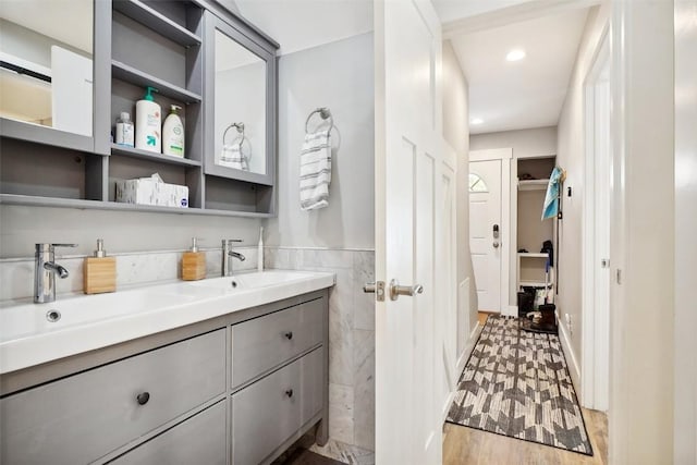 bathroom with a wainscoted wall, tile walls, recessed lighting, vanity, and wood finished floors