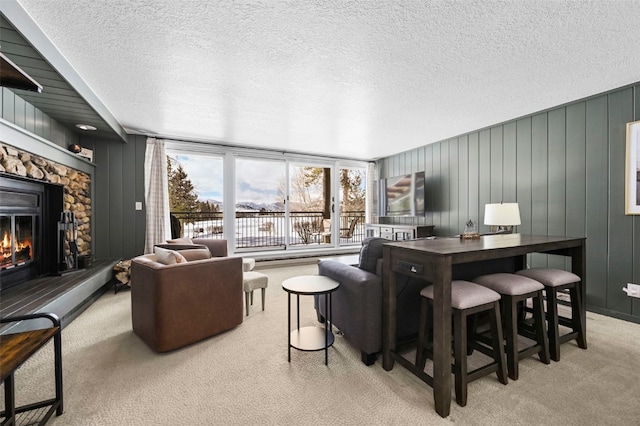 living area with light colored carpet, a fireplace, and a textured ceiling