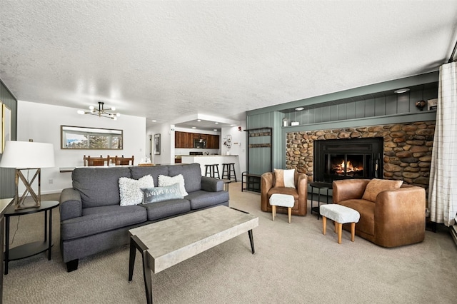 living room with a textured ceiling, a fireplace, carpet flooring, and a notable chandelier