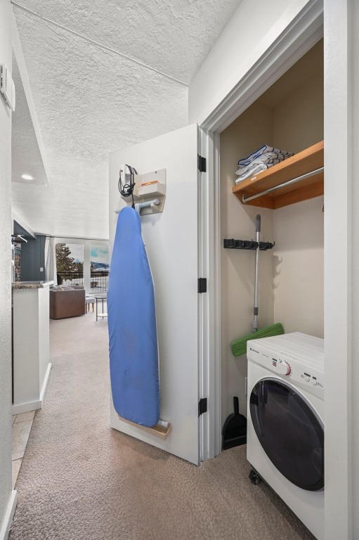 laundry area with washer / dryer, laundry area, carpet flooring, and a textured ceiling