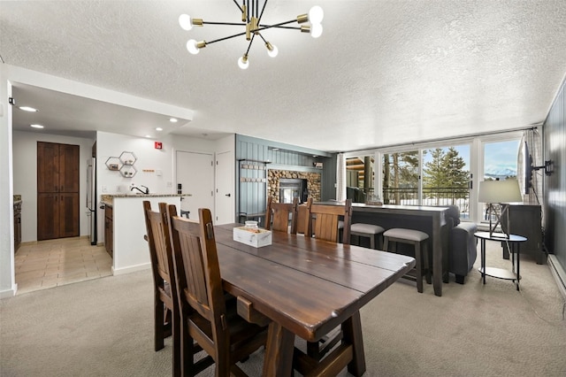 dining area with a textured ceiling, an inviting chandelier, and light colored carpet