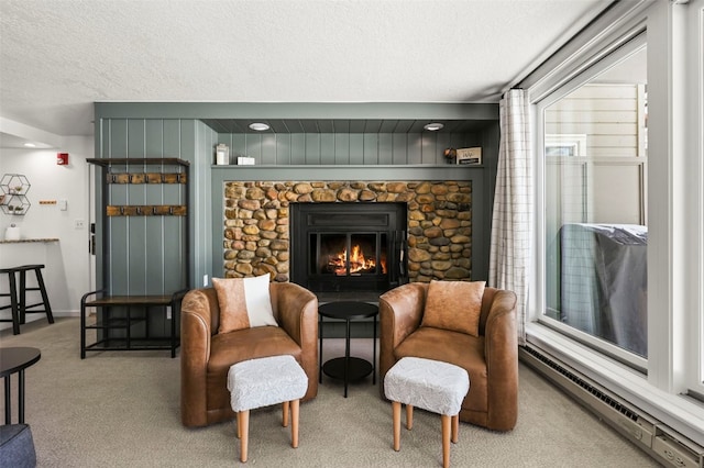 sitting room with carpet floors, a fireplace, baseboard heating, and a textured ceiling