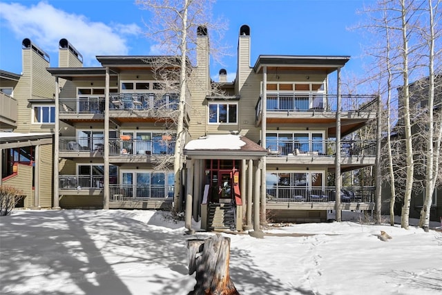 snow covered property with a chimney