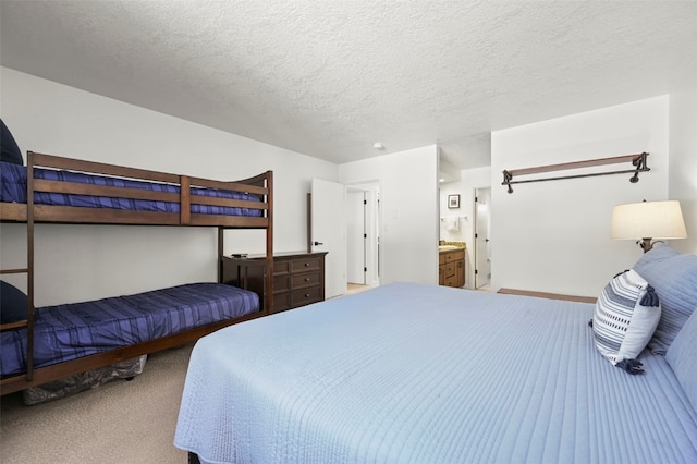 bedroom featuring carpet floors, a textured ceiling, baseboards, and ensuite bathroom