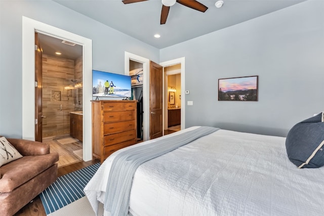 bedroom with ceiling fan, ensuite bath, wood finished floors, a walk in closet, and a closet