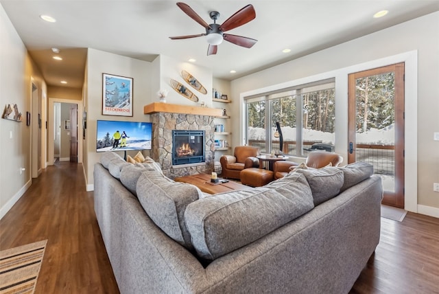 living area featuring recessed lighting, a ceiling fan, a stone fireplace, wood finished floors, and baseboards