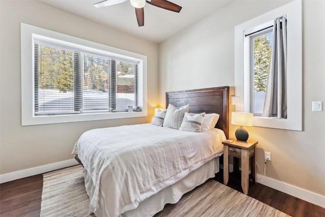 bedroom with a ceiling fan, multiple windows, baseboards, and wood finished floors