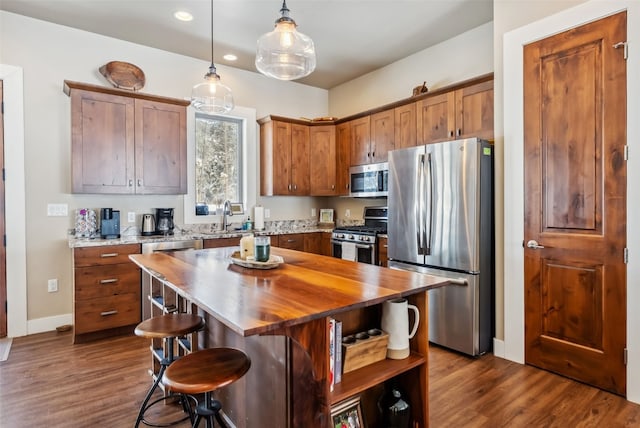 kitchen featuring stainless steel appliances, butcher block counters, a sink, dark wood-style floors, and brown cabinetry