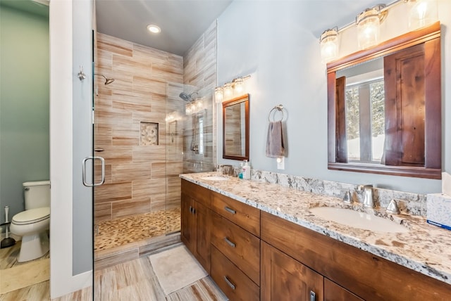 bathroom featuring a sink, a shower stall, toilet, and double vanity