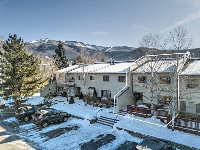 snow covered back of property with a deck with mountain view