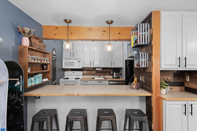 kitchen featuring a kitchen breakfast bar, white cabinetry, white appliances, and backsplash