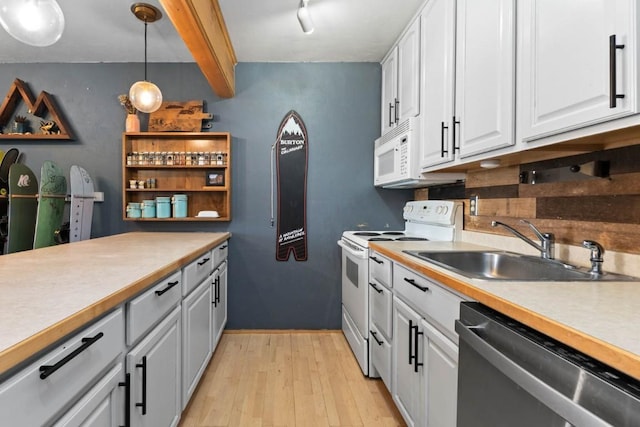 kitchen with beam ceiling, sink, hanging light fixtures, white appliances, and white cabinets