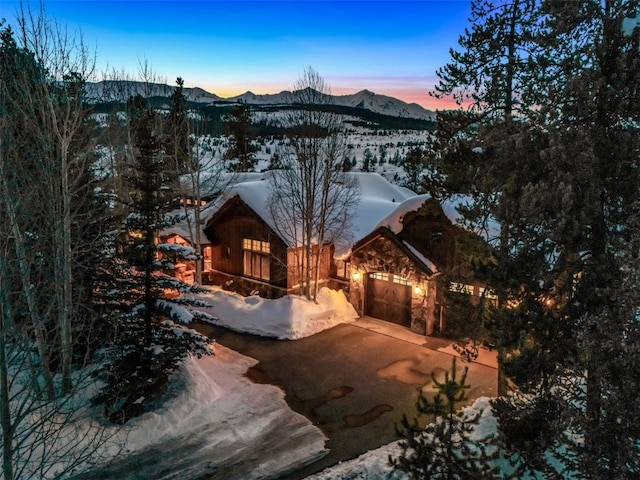 view of front facade with a mountain view, an attached garage, stone siding, and driveway